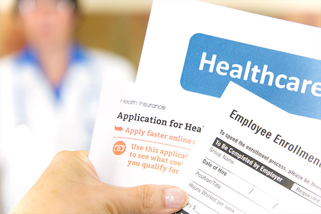 Open enrollment healthcare benefits forms with a medical doctor in the background