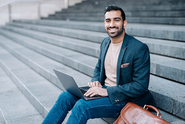 Employee sitting on stairs in downtown Atlanta with computer reporting ethics hotline status