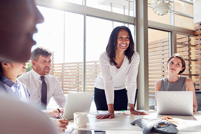 Smiling female HR manager listening to colleagues at organizational development meeting